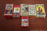 Six tarot and fortune-telling card decks in their boxes, lined up on a table.