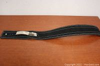 Full view of medium-sized black weight lifting belt laid flat showing belt length, white edge stitching, and silver buckle.