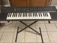 Front view of Casio CT-420 keyboard on black X-style stand, showing keys and control panel