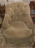 Front view of a single tufted upholstered accent chair in beige fabric with cushioned seat and rounded arms.