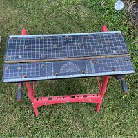 Top view of the construction work table showing measurement grid, protractor, and clamp holes on the tabletop
