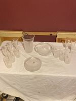 Full set of etched crystal glassware including decanter, glasses, bowl and ashtray arranged on white cloth