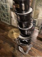 Photo showing stacked black kids drums and cymbal with pedal setup on wood floor