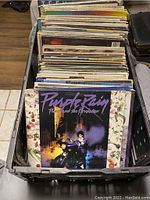 Plastic crate filled with vinyl LP records, top record is Prince 'Purple Rain'