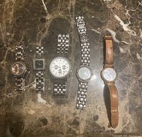 Full view of five watches in lot with different brands and styles on marble surface