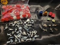 Top view showing numerous silver Monopoly tokens along with a bag of dice and various red pieces