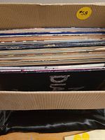 Box filled with various used vinyl records showing the thickness and variety of the lot.