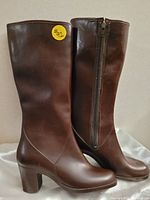 Side view of brown leather boots showing smooth surface, mid-calf height, and side zipper.