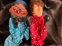 Photo showing two hand puppets, one cartoon-like with a blue hat and striped shirt, the other more realistic boxer character in red polka dots shirt, both with boxing gloves.