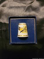 Bone porcelain thimble with yellow wren illustration and gold trim, displayed in blue box.
