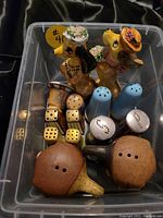 Photo of all 7 pairs of salt and pepper shakers in the plastic bin showing various materials including ceramic, metal, plastic; includes dog figurines, dice, mushroom shapes
