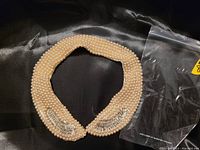 Front view of the pearl beaded collar with rhinestone fan details on a black satin background.