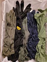 Top view of five pairs of women's fashion gloves laid out on white fabric, showing various colors and ruched wrist detailing.