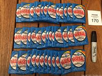 Full lot showing 39 unopened blue 1989 OPC Major League Baseball wax packs arranged on wooden surface next to marker for scale.