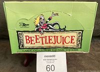 Closed green wax box with Beetlejuice character artwork and branding visible, showing wear and tear.