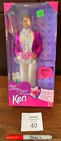 Front view of the unopened 1992 Secret Hearts Ken Doll box showing doll in magenta and white formal outfit, white shoes, pink heart-shaped accessory, and red string accessory.