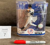 Front view of unopened sealed packaging showing Derek Jeter in batting pose with bat, wearing Yankees uniform and helmet. Packaging includes Yankees logo and holographic sticker.