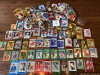 Wide view of the hockey card collection spread on wood floor, showing multiple rookie and regular cards including some in protective holders.