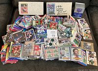 Overview of large piles of football cards with many visible cards from multiple years and sets spread out on a couch and floor.
