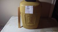 Yellow hard plastic Coleman carry case with handle and embossed logo on front.