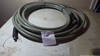 Full view of coiled grey compressor hose on table with an auction tag.