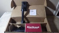 New Kwikset door handleset in original box, showing handle and latch hardware inside.