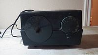Front view of the vintage black Motorola radio showing the large speaker and tuning knobs on the front panel.