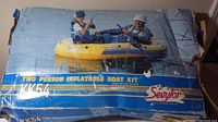 Box showing two people fishing on yellow and blue Sevylor inflatable boat, model KK54