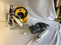 Power bars and extension cords laid out, showing yellow reel cord, black and white power bars with multiple outlets.