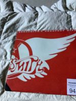 Close up photo showing red and white logo on the vinyl record with Aerosmith wing design.