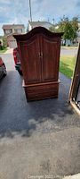 Full view of a solid wood maple armoire with walnut finish showing two doors and two drawers.