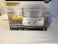 Front view of the boxed Black & Decker 4 quart steamer and rice cooker showing product image, branding, and features including 75 minute timer and auto shut off.