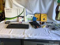 Photo of all computer items including router, keyboard, adapters, storage and software