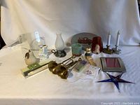 Overall view of assorted household decorative items on white background including candle sticks, figurines, glass star, metal tray, and more.
