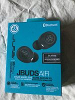 Front of box showing JLab JBuds Air true wireless earbuds, Bluetooth, 24+ hours playtime, and key features.