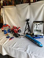 Photo showing all items in lot including toys, telescope, and toy vehicles.