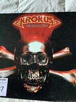 Front cover of Krokus Headhunter LP 1983 showing metallic skull and bone artwork with band name and album title