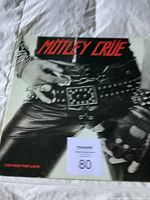 Front cover of Motley Crue 'Too Fast For Love' vinyl record showing the belt and stud detail with red title text.