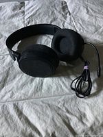 Full view of black SteelSeries headphones with foam ear cushions, microphone boom, and wired cable coiled.