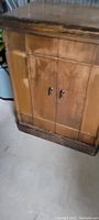 Closed wooden radio cabinet with two doors and metal handles showing worn finish.