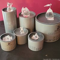 Overview of all six Swarovski figures atop original round and cylindrical boxes