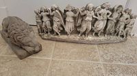 Both stone ornaments including the sleeping lion and line of dancing angels shown together on floor tile surface.