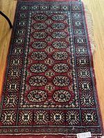 Full view of red and blue tapestry floor runner with detailed pattern and fringed end.