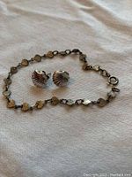 Gold-tone 80s inspired bracelet with heart-shaped and shell-like links alongside matching shell-shaped stud earrings