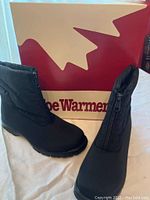 Side view of black tall boot with Toe Warmers box in background