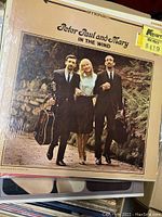 Close-up photo of Peter, Paul and Mary - In The Wind LP album with plastic cover and a price sticker.