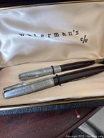 Close-up of Waterman's fountain pen set inside the cream satin-lined box with two pens, silver caps and black bodies.