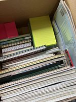Box packed with various spiral notebooks, sticky notes, and other paper stationery items.