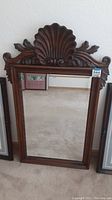 Large dark wood framed beveled mirror with shell and scroll carved crest at the top.