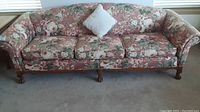 Front view of floral 3 seater sofa with three removable cushions and a decorative white pillow on center cushion.
